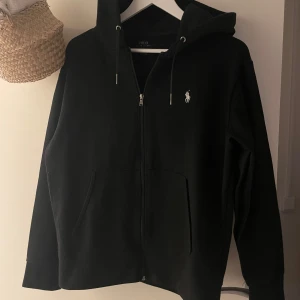 Svart hoodie från Ralph Lauren - Snygg svart hoodie från Ralph Lauren med dragkedja och huva. Jättefint skick. Storlek: M men mer som S