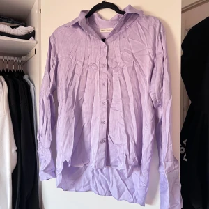 Ljuslila skjorta från MQ - Säljer en stilren ljuslila skjorta från MQ. Skjortan har långa ärmar och knappar framtill. Perfekt för en chic och avslappnad look. 💜 Aldrig använd! Önskar du veta exakta mått? Tveka inte att höra av dig!