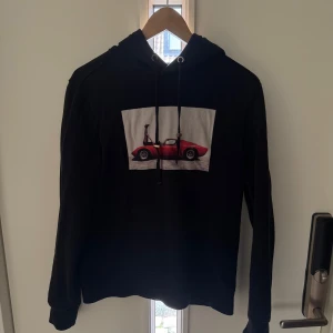Svart hoodie från Limitato - Säljer en svart hoodie från Limitato i storlek S med en cool bild av en röd sportbil på framsidan. Hoodien har en klassisk design med dragsnören i huvan och ribbade muddar vid ärmslut och nederkant. Bara att höra av er vid frågor och fler bilder