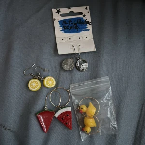 Färgglada örhängen i olika motiv och stilar. - Säljer ett set med fyra par örhängen i olika motiv. Ett par med citroner i gul och vit färg, ett par med vattenmeloner i röd, grön, vit och svart färg, ett par med ankor i gul och orange färg och ett par med olika svartvita mönster. Perfekt för att lägga till en lekfull touch till din outfit!