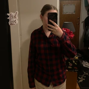 Röd och svart rutig skjorta från H&M - Säljer en röd och svart rutig skjorta från H&M:s L.O.G.G. kollektion. Skjortan har långa ärmar och en klassisk krage. Perfekt för en avslappnad stil.