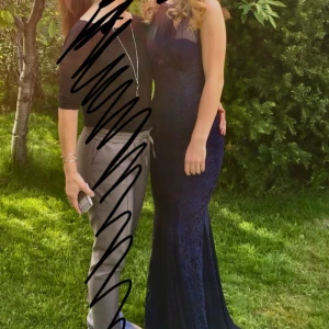 Anna Field - Mörkblå långklänning stl. 34 - Elegant mörkblå långklänning med spetsdetaljer och transparent överdel från Anna Field. Klänningen har en hög halsringning och en figurnära passform som ger en stilren siluett. Perfekt för speciella tillfällen.