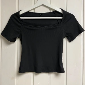 Svart ribbad topp - Snygg svart ribbad topp med korta ärmar och en stilren design. Perfekt för en trendig look.