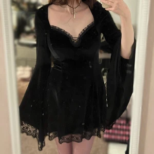 Jättefin svart sammet klänning med spets - Snygg svart klänning i sammet med långa vida ärmar och spetsdetaljer vid halsringning och fåll. Osäker på märke då det var en present men kvaliten är bra! Tyvärr har jag bara användt den en gång, dock är det inget fel på den!