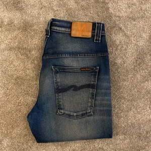 Blå jeans från Nudie Jeans - Snygga blå jeans från Nudie Jeans med en klassisk femficksdesign. De har en straight passform och är tillverkade i slitstarkt denim. Perfekta för en avslappnad stil med en snygg tvättad look.