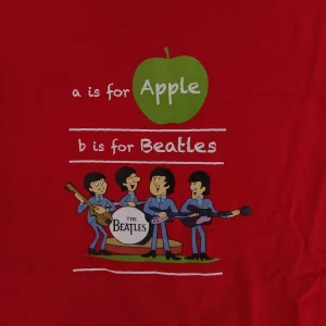 Röd Beatles t-shirt - Säljer en unik röd t-shirt med Beatles-tryck. Oversized S. Framsidan har en bild av bandet och texten 'a is for Apple, b is for Beatles'. Mycket fint plagg 🌟 100% bomull