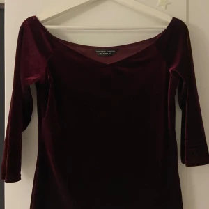 Vinröd sammetstopp från Dorothy Perkins - Snygg vinröd topp i mjuk sammet från Dorothy Perkins. Den har en elegant v-ringning och trekvartsärmar, perfekt för en stilren look. Passar utmärkt till både jeans och kjol.