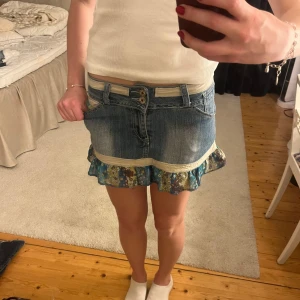 Jeanskjol med volangdetalj - Snygg jeanskjol från My Industry med volangdetalj i blått och blommigt mönster. Kjolen har knappar fram och fickor både fram och bak. Midjemått: 37cm rakt över. Längd: 28 cm. Använd gärna köp nu 💕💕