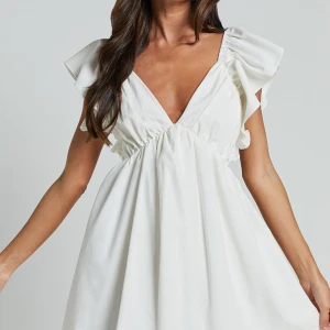 Vit klänning med volangdetaljer - Elegant vit klänning med v-ringad fram och öppen rygg. Klänningen har volangdetaljer vid axlarna och en knytning i ryggen. Perfekt för sommarens festligheter. Stl S ifrån showpo, endast testad med prislapp kvar💕