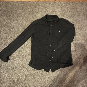 Grå Ralph lauren skjorta  - Riktigt snygg och bekväm skjorta. Har tyvär växt ur som ni ser på bilden  Vid minsta fråga är det bra att kontakta mig! Skicket är bra inga defekter 9/10 Storlek S-M passar 175-183 Ny pris runt 1500 