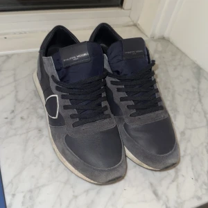 Blåa  sneakers från Philippe Model - Snygga blåa  sneakers från Philippe Model med svarta snören och vita detaljer. Skorna har en stilren design med en bekväm sula, perfekt för en avslappnad stil. Nypris på dessa är 3500kr köpta från hemsidan.
