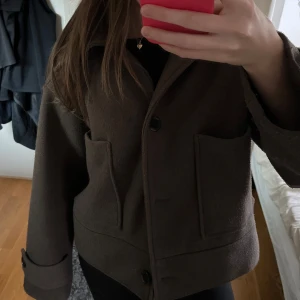 Brun kappa med knappar - Säljer en stilren brun kappa med knappar framtill och stora fickor. Jackan har en klassisk krage och långa ärmar. Perfekt för höst och vår! Pris kan diskuteras! Säljer en likadan i svart också!