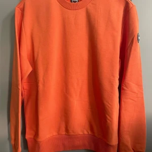 Orange tröja från italienska Colmar - Säljer en snygg orange tröja från Colmar. Tröjan har en rund halsringning och långa ärmar. Perfekt för en färgglad stil. Märkeslogga på ärmen ger en extra touch. Passar bra till både jeans och chinos.