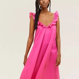 Rosa klänning med volangdetaljer - Säljer en härlig rosa klänning med volangdetaljer vid axlarna. Klänningen har en v-ringad design och är i en luftig passform. Perfekt för sommarens varma dagar!