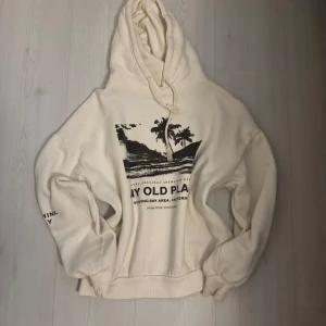 krämvit hoodie från Pull&Bear - Säljer en kräm vit hoodie från Pull&Bear med tryck av palmer och text på framsidan 💕