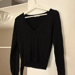 Svart glittrig kofta - Snygg svart glittrig kofta med v-ringning och knappar framtill. Hör av er vid funderingar eller om ni vill ha bilder med hur plagget sitter på mig. Titta gärna in mina andra plagg!