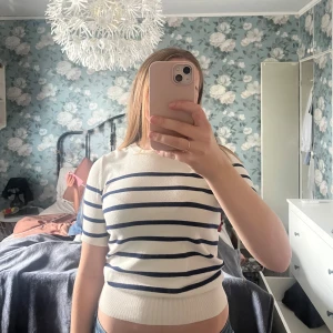 En randig kortärmad tröja ifrån Zara - Superfin vit tröja från Zara med marinblå horisontella ränder. Kortärmad och rund halsringning, sitter snyggt och har en lite croppad passform. Perfekt till jeans eller kjol.