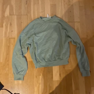 Grön sweatshirt från H&M Divided XS - Enkel och stilren ljusgrön sweatshirt från H&M Divided i storlek XS. Tröjan har rund halsringning, långa ärmar och breda muddar vid ärmslut och nederkant. Perfekt för en chill och avslappnad look.