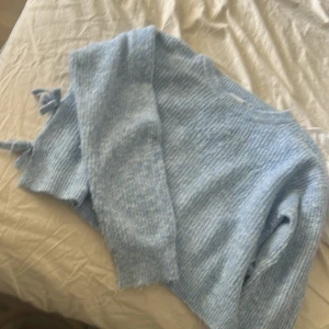 Ljusblå stickad tröja från Name It - Supermysig ljusblå stickad tröja från Name It med rund hals och långa ärmar. Tröjan har ribbade muddar och fina knytband i sidorna som ger en extra touch. Perfekt för lager-på-lager och chill dagar.