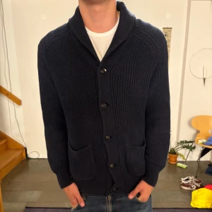 Mörkblå kofta från Polo Ralph Lauren - Säljer en mörkblå grovstickad polo Ralph lauren kofta. Perfekt för dig som vill ha en lite mer avslappnad stil. Den är i väldigt bra skick. På bilden är fem knappar knäppta men man kan även knäppa en till längst upp. Skriv om ni vill ha bild på det eller på annat.                                           Modellen är 184 och väger 75.                                                                                   // Victor ✌️❤️