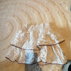 Vit volangkjol från Pomp de Lux - Supersöt vit kortkjol från Pomp de Lux med små mörka prickar och volanger. Kjolen är väldigt strechig och passar xxs-s