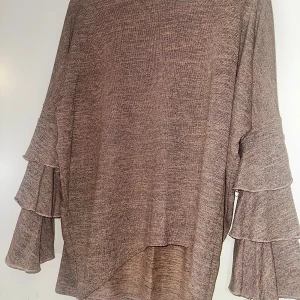 Volangtröja S från Chica London - Superfin beige tröja från Chica London med långa ärmar och snygga volangdetaljer på ärmarna. Mjuk och skön i materialmix av viskos och polyester. Lite längre baktill.