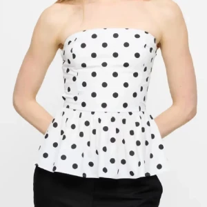 Prickig bandeau topp från Bik Bok - Supersöt vit bandeau topp från Bik Bok med svarta prickar. Köpt på plick och har endast testat den. Jättebra skick förutom att det är ett litet hål vid dragkedjan som knappt syns. Säljer för att den tyvärr var för liten. Först till kvarn.