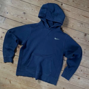 Mörkblå Nike hoodie med huva - Mörkblå hoodie från Nike med klassisk logga på bröstet. XL i barnstorlekar men passar som S. Aldrig använd, alltså i perfekt skick.
