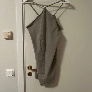 Grön  klänning H&M - Snygg grön klänning från H&M med smala axelband som korsas i ryggen. Modellen är rak och enkel, med en stilren look och mjukt material. Perfekt för dig som gillar minimalistisk stil och vill ha något bekvämt men ändå trendigt.Katt finns i hemmet 