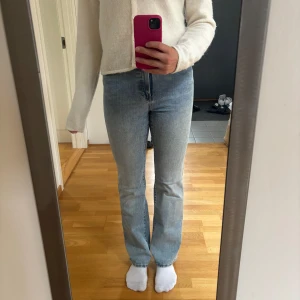 Ljusblå bootcut jeans med medelhög midja - Snygga ljusblå jeans med bootcut passform och hög midja. Klassisk femficksmodell i mjukt denimtyg. Jeansen har dragkedja och knapp framtill samt raka ben som släpper ut lite nertill.