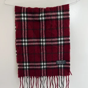 Burberry halsduk - Säljer en röd halsduk från Burberry som är en perfekt accessoar till din outfit. Halsduken är i fint skick och är självklart äkta, ett äkthetscertifikat följer med vid köp. Hör av er vid minsta fundering🙏