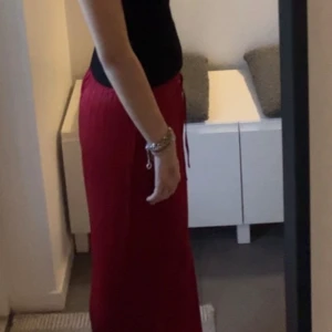 Röda wide byxor från Index, strl S - Snygga röda byxor från Index i återvunnen polyester. De har bred passform, resår i midjan och dragsko för extra komfort. Byxorna är raka och vida i modellen, perfekta för en chill och trendig look.