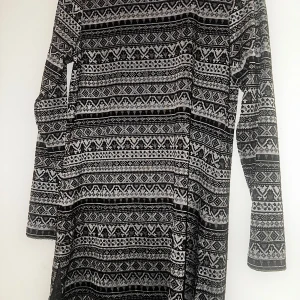 Mönstrad, långärmad klänning S/M - Svartvit klänning från Bik Bok med grafiskt mönster i olika geometriska former. Långärmad och i mjukt material med inslag av polyester, viskos och elastan. Perfekt för dig som gillar en stilren men ändå unik look.