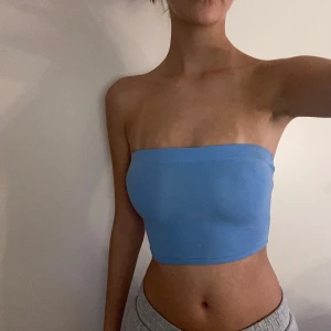 Blå bandeau tubtopp från H&M Divided - Säljer en ljusblå bandeau tubtopp från H&M Divided. Toppen är ärmlös och axelbandslös med en enkel, tight passform. Perfekt för varma dagar och enkel att matcha med jeans eller kjol. Mjuk och stretchig bomullskvalitet.