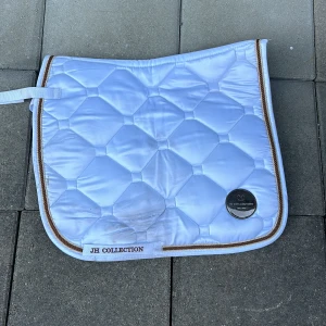 Fint schabrak från Hööks! - Fint schabrak i storlek cob från Hööks. Schabraket är vitt med guld och brun kant, schabraket är inte tvättat! Dressyr modell.