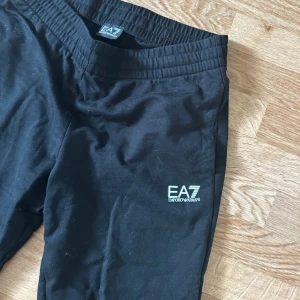 Svarta EA7 mjukisbyxor - dress från EA7 Emporio Armani. Använt väldigt få gånger, finns fläck från tvättmedel på koftan men går 100% bort i tvätten.                                         