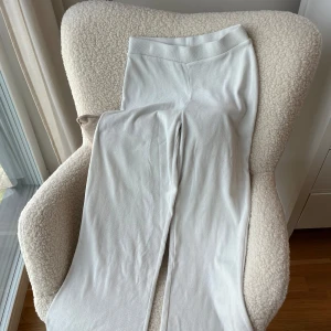 Vita ribbade mjukisbyxor Gina Tricot - Säljer ett par vita mjukisbyxor från Gina Tricot i storlek S. Byxorna har ribbad midja och är gjorda i mjukt stickat material. De har en rak och relaxed passform med breda ben, perfekta för chill dagar hemma eller när du vill vara extra comfy. Det finns lätt missfärgnad på bilden. Vid köp, kommer de skrubbas bort med galltvål. Om de återstår, kontaktas köparen med info❤️