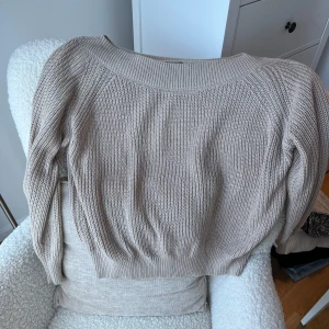 Beige stickad tröja från Lindex - Säljer en beige stickad tröja från Lindex i storlek M. Tröjan har en bred ribbad rund halsringning och långa ärmar. Den är grovstickad och har en relaxed passform med ribbade muddar vid ärmslut och nederkant. Perfekt för lager-på-lager under kyliga dagar.