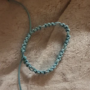 Blått handgjort makraméarmband - Snyggt handgjort armband i ljusblått med makraméknutar och små transparenta pärlor insydda längs hela bandet. Justerbar storlek med snörning, perfekt för dig som gillar unika accessoarer och vill sticka ut lite extra.