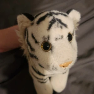 Gosedjur  - Bilderna visar ett gosedjur i form av en vit tiger med svarta ränder och stora ögon. Det är en mjuk leksak