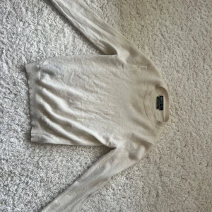 Kräm vit cashmere  tröja från Mango - En enkel och stilren kräm vit cashmere tröja från Mango. Tröjan har rund hals, långärmade ärmar och är gjord i mjukt material som känns skönt mot huden. Perfekt för lager-på-lager och passar till jeans eller kjol. Klassisk passform och neutral färg. Köpt för 1000 kr men har fått en litet hål  på armen men som man lätt kan sy ihop och som knappt märks men säljer billigare på grund av det. 