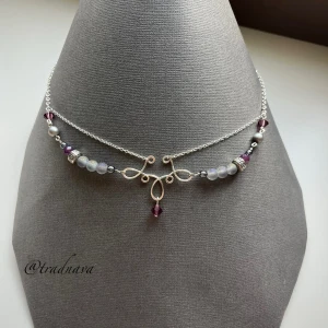 ”Norna” - Handgjort halsband i silverpläterad koppartråd med dekorativa lila och grå pärlor. Centralsmycket har en lila kristall från Preciosa som hänger i mitten (finns ytterligare två Preciosa-kristaller längs med kedjan). Kedja, lås, bindöglor och hattpinnar är i silverplätering. Alla pärlor är tjeckiska glaspärlor förutom de två metallpärlorna. Jag kan enkelt ändra längd/storlek på mina smycken utan extra kostnad, det är bara att höra av dig!🌸