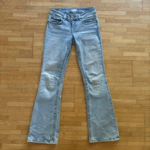 Ljusblå bootcut jeans från Gina Tricot - Snygga ljusblå bootcut jeans från Gina Tricot i storlek 36. Klassisk femficksmodell med två bakfickor med lock och knapp, samt bälteshällor. Jeansen har låg midja och är tillverkade i mjukt denimtyg som ger en chill vibe.