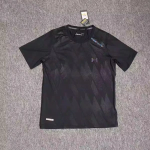 Svart träningst-shirt Under Armour - Snygg svart t-shirt från Under Armour med diskret geometriskt mönster och logga på bröstet. Perfekt för träning, med korta ärmar och rund hals. Materialet är lätt polyester som andas och håller dig fräsch under passet.