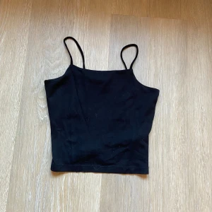 Svart linnetopp med smala band - En svart linnetopp med smala axelband och rak halsringning.