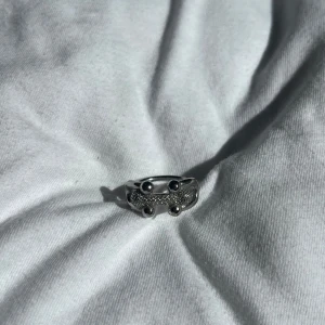 Silvrig chunky ring med detaljer - Säljer en cool silvrig ring med chunky design och fyra runda detaljer på ovansidan. Ringen har en glittrig yta i mitten. Perfekt för dig som vill ha något unikt.
