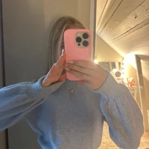 Ljusblå croppad stickad tröja - Superfin ljusblå stickad tröja med croppad passform och breda, puffiga ärmar. Tröjan har ribbade muddar vid ärmslut och midja, vilket ger en snygg siluett. Perfekt att styla med höga jeans eller kjol för en chill look.