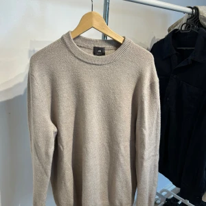 Beige stickad tröja från H&M - Säljer en beige stickad tröja från H&M i regular fit. Tröjan har rund halsringning och långa ärmar med ribbade muddar. Perfekt för dig som gillar enkel och clean stil. Passar dig som vill ha en basic tröja med skön känsla.