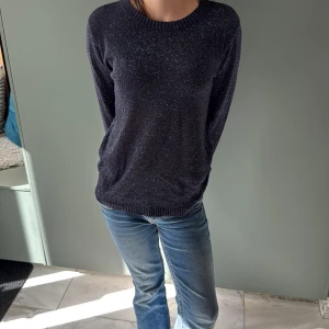 Glittrig mörkblå tröja från Kids Only - Snygg mörkblå stickad tröja från Kids Only med glittriga inslag som ger en cool shimmer-effekt. Tröjan har rund hals, långa ärmar och ribbade muddar vid hals, ärmslut och nederkant. Perfekt för dig som gillar lite extra bling i vardagen.