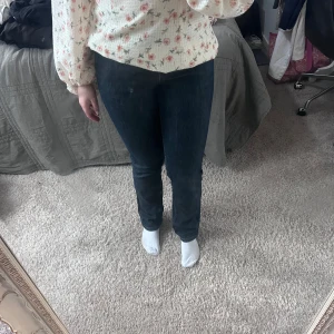 Mörkblå raka jeans - Snygga mörkblå jeans med rak passform och klassisk midja. Jeansen har en enkel design utan synliga detaljer och sitter riktigt bra över benen. Perfekta för dig som gillar en clean och tidlös look. Materialet är klassiskt jeans och färgen är djupblå.